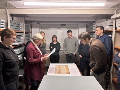 Der Arbeitskreis „Archive im HSK“ zu Besuch im Landesarchiv NRW in Münster. Die Leiterin der Abteilung, Mechthild Black-Veldtrup (links mittig) zeigt eine Papst-Urkunde mit dem Kloster Wedingshausen aus dem Mittelalter.